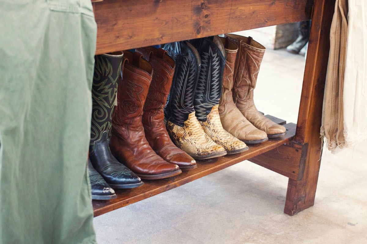 Several pairs of boots lined up on a wooden shelf.